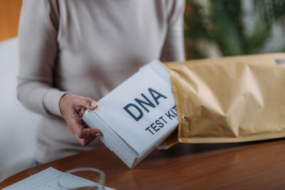Midsection of woman putting dna kit in envelope