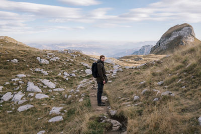 Side view of man standing on land against sky