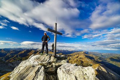 Rear view of man standing on mountain against sky