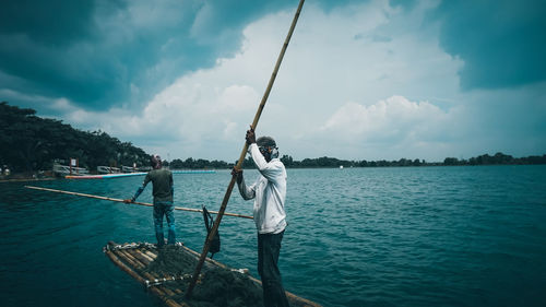 Man fishing in sea against sky