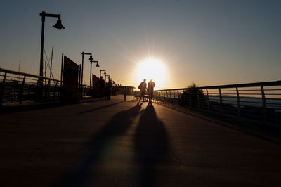 Man walking on bridge against sky during sunset