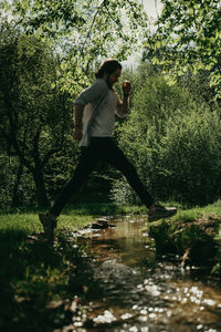 Trail running in the forest jumping over the stream.