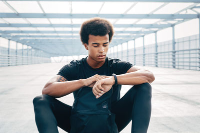 Young man looking away while sitting on wall