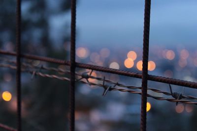 Close-up of barbed wire against defocused lights