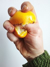 Close-up of hand holding apple against white background