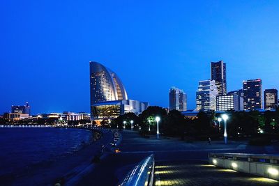 Illuminated cityscape against clear blue sky at night