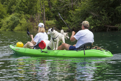 People on boat in river against trees