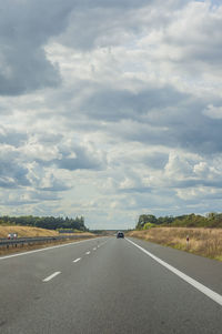 Surface level of road against cloudy sky