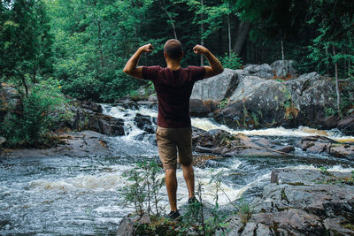 Rear view of boy standing on rock in forest