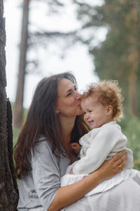 Happy mother and daughter against trees