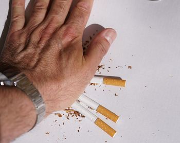 Close-up of hand crushing cigarettes