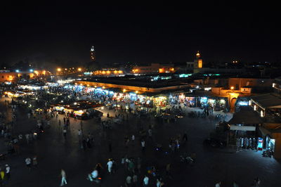 Crowd at illuminated city against sky at night