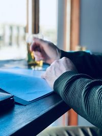 Cropped hand of man reading file on table