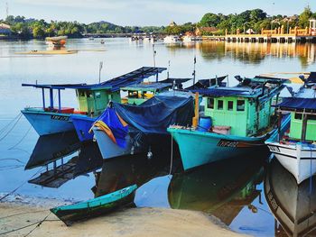 Fishing boats moored at lake against sky