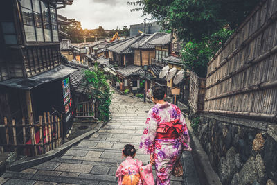 Rear view of woman walking on street amidst buildings in city