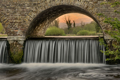 Arch bridge over river against trees