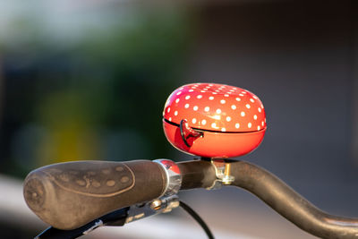 Red bike bell with white polka dots in evening sunshine and blurred background for healthy mobility