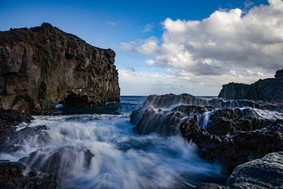 Scenic view of rocks in sea against sky