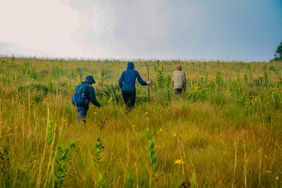 Rear view of woman walking on field against sky