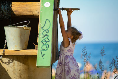 Rear view of young woman standing against wall