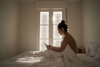 Woman sitting on bed at home