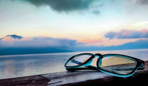 Close-up of sunglasses against sky during sunset