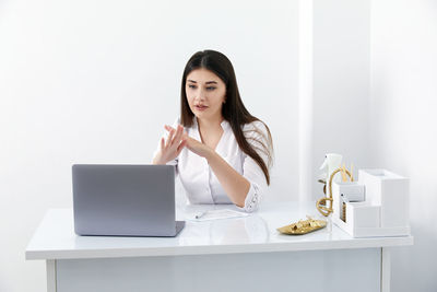 Young woman using laptop while sitting on table