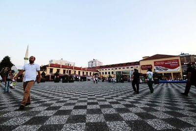 People standing in town square against clear sky