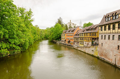 River amidst trees and buildings against sky