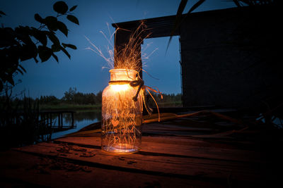 Illuminated lantern on table against sky at night