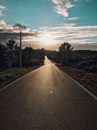 Surface level of road along landscape at sunset