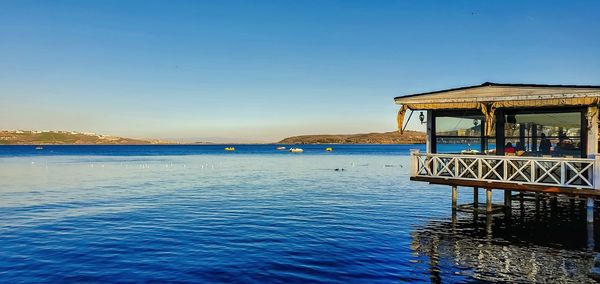 Pier over sea against clear blue sky