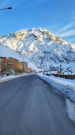 Road amidst snowcapped mountains against sky