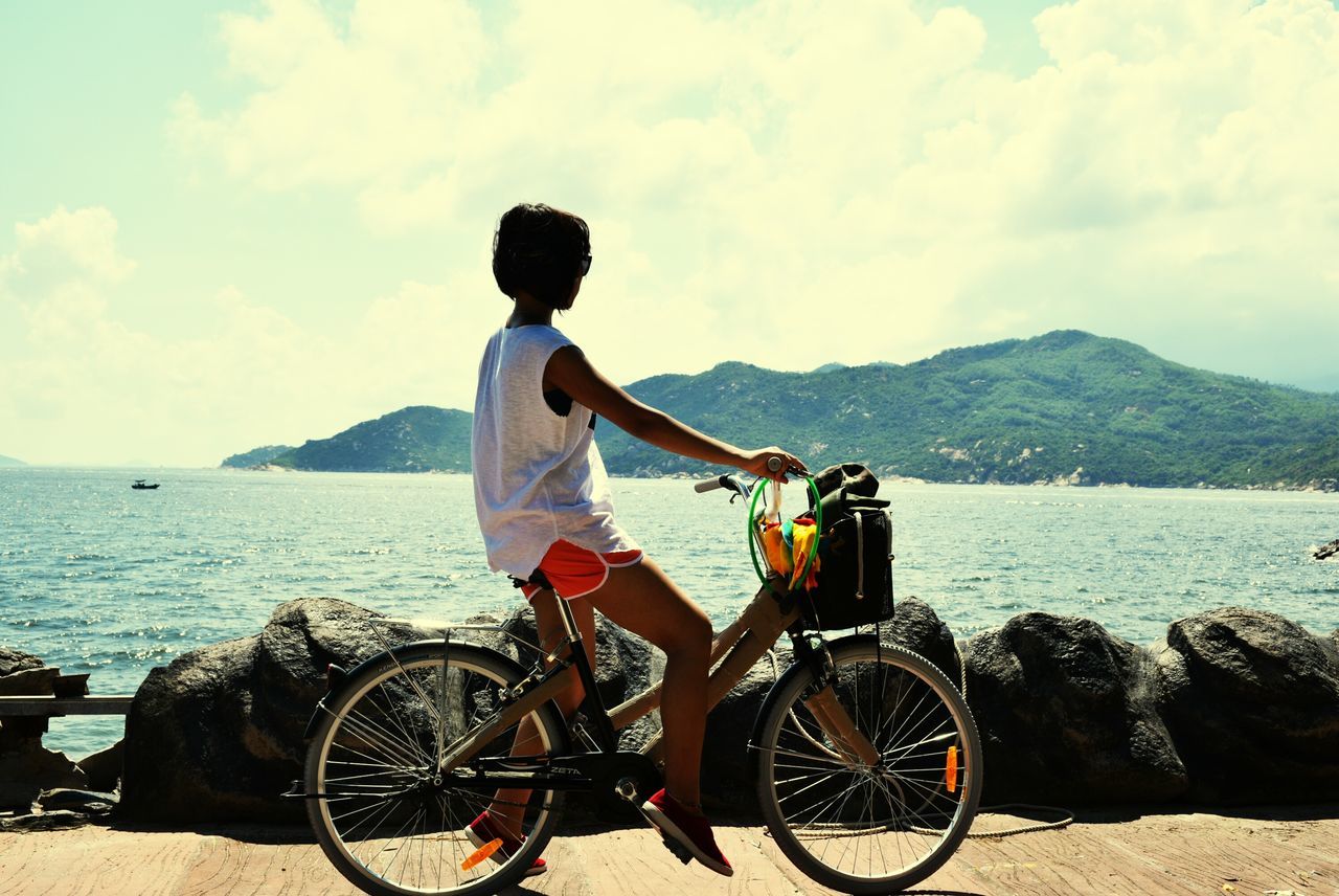 bicycle, transportation, mode of transport, lifestyles, leisure activity, sky, water, land vehicle, sea, men, full length, cloud - sky, rear view, travel, casual clothing, riding, side view, mountain