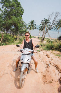 Portrait of man riding motor scooter at beach