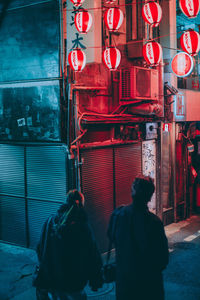 Rear view of people walking on illuminated street