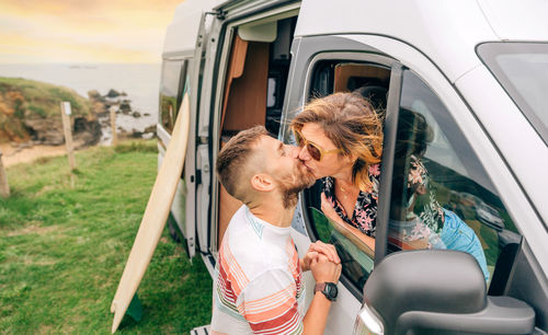 Couple kissing through the camper van window during a trip