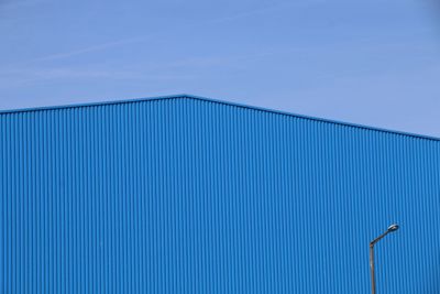 Low angle view of blue factory against sky