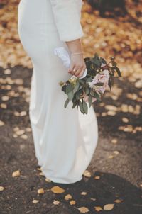 Low section of bride holding white flower