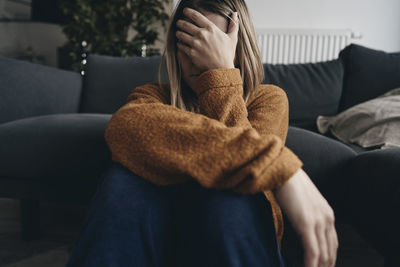 Depressed woman sitting by sofa at home