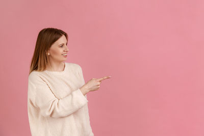 Young woman standing against yellow background