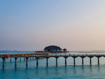 Pier over sea against clear blue sky