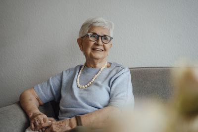 Smiling senior woman sitting on sofa at home