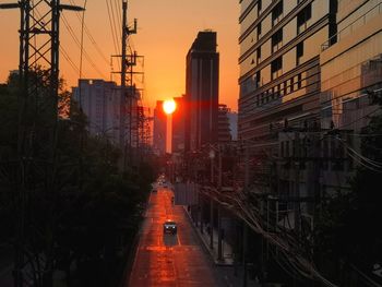 Road amidst buildings against sky during sunset