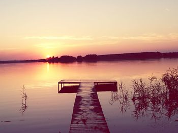 Jetty over river against sky during sunset