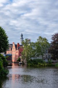 River amidst buildings and trees against sky