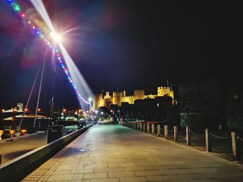 Illuminated street lights on footpath in city at night