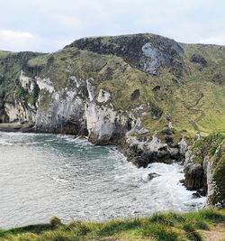 Scenic view of rocks by sea against sky