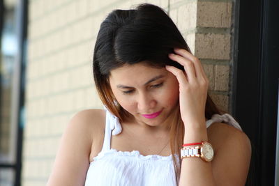 Close-up of young woman posing against wall