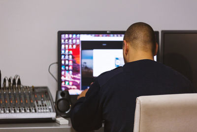 Rear view of tv editor working with sound mixer at workspace